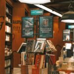 A cozy bookstore interior showcasing a variety of stacked books under warm lighting.