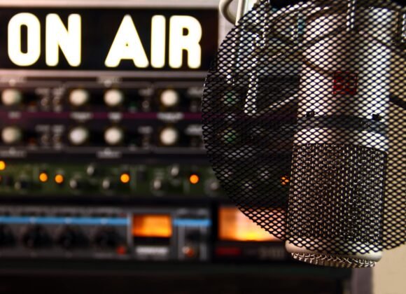 Close-up of a radio microphone and control panel in an illuminated studio.