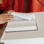 Close-up of a person reading the Bible at a church podium during a religious ceremony.