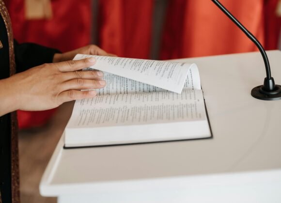 Close-up of a person reading the Bible at a church podium during a religious ceremony.